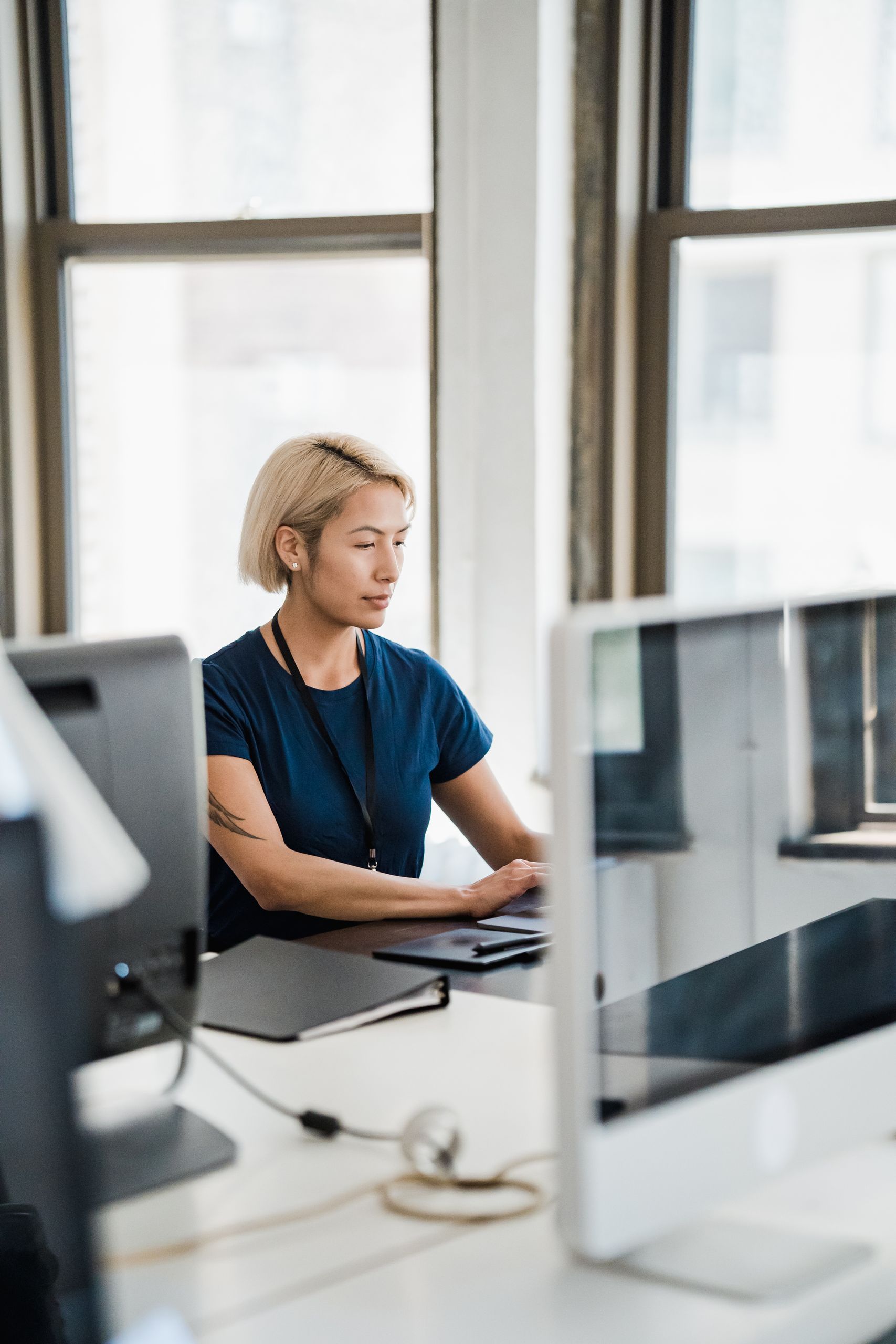 A focused woman working on a computer in a bright, modern office setting.