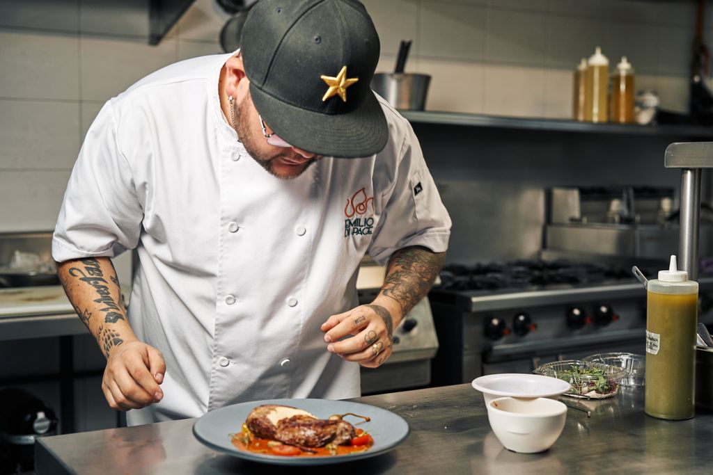 Chef in restaurant kitchen meticulously plating a gourmet dish. Culinary artistry captured in action.