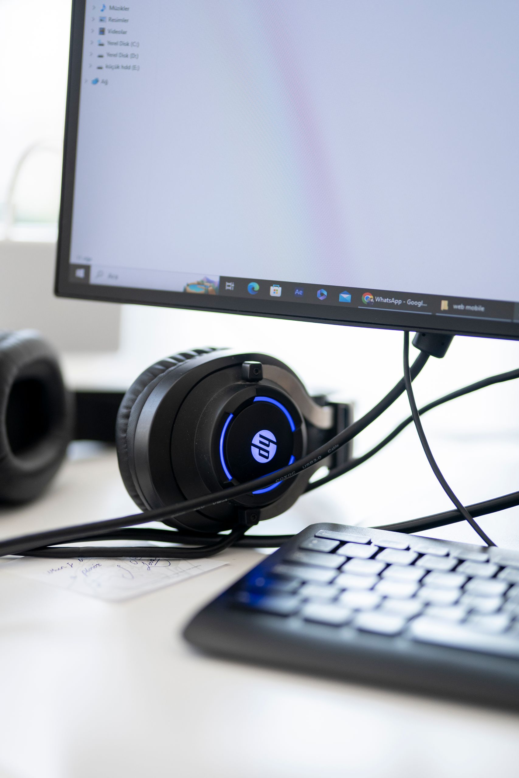 Close-up view of a modern workspace setup featuring headphones, monitor, and keyboard.