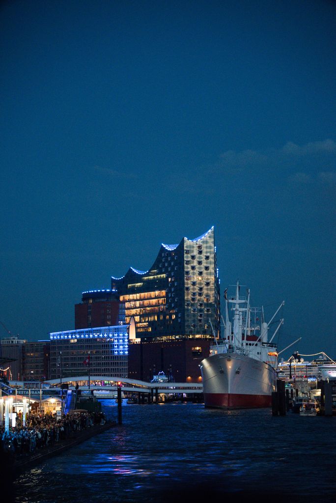 View of the Elbphilharmonie and a ship in the Hamburg harbor at night.